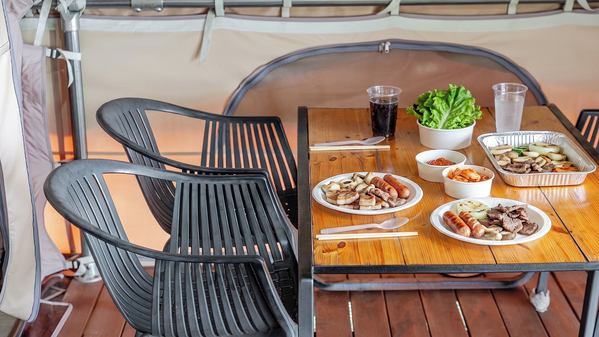 A dining table with plates of food, a drink, and a salad bowl.