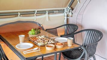 A dining table set with plates, bowls, and a tray of food, surrounded by chairs.