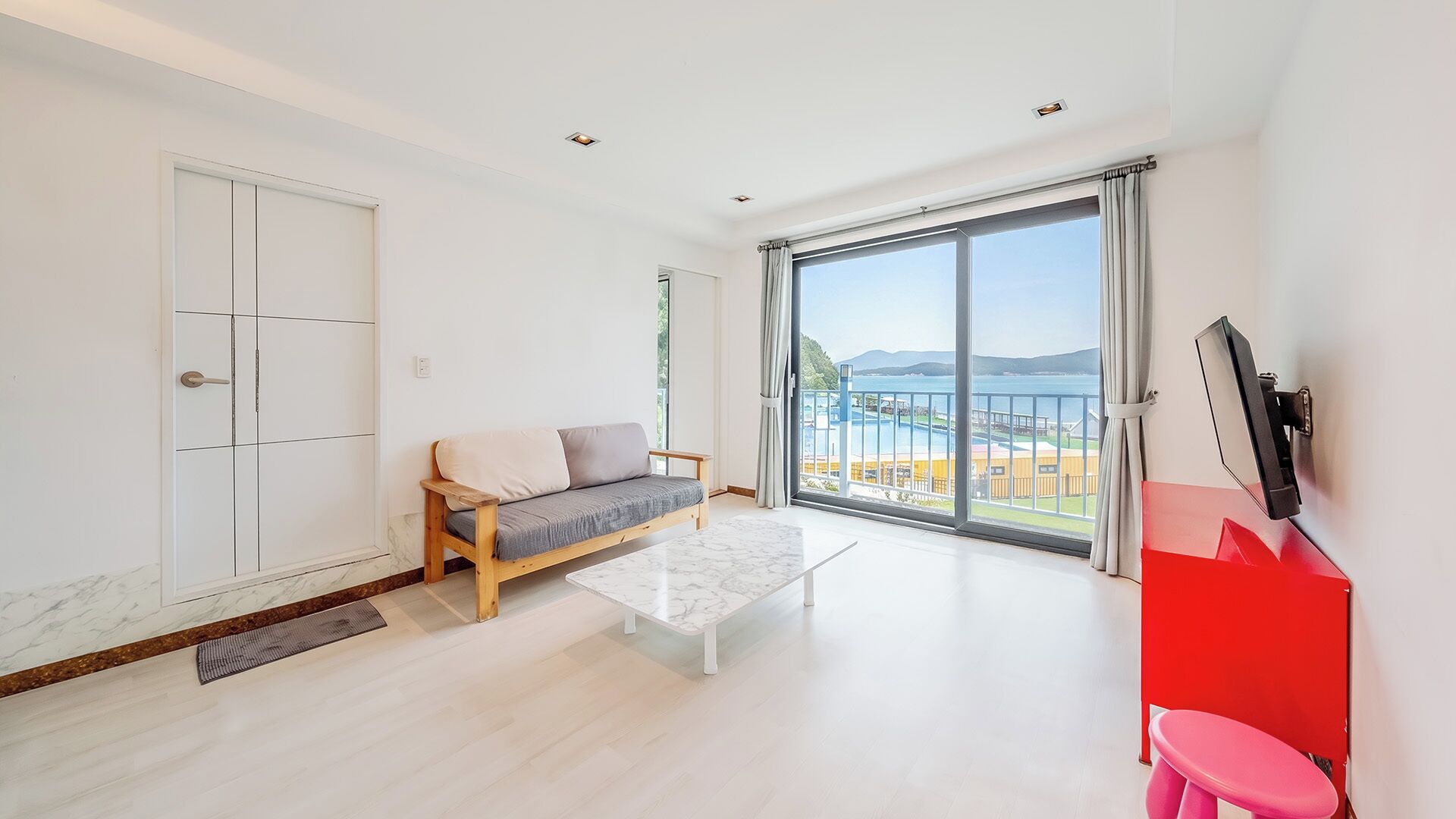 Una sala de estar moderna con un sofá, una mesa de centro y un amplio ventanal corredero que da a un balcón con vistas.