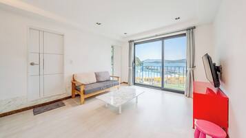 Una sala de estar moderna con un sofá, una mesa de centro y un amplio ventanal corredero que da a un balcón con vistas.