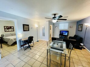 A compact living space with a bed, a desk, a dining table, and a TV. - Fabens TX. Jewel Apartment, 2 Bedroom, 1 Bathroom. (Fabens)