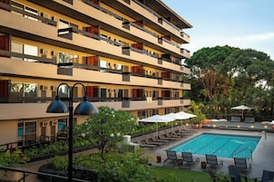 Una piscina al aire libre, sombrillas, sillones reclinables de piscina