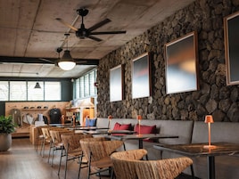 A restaurant interior with stone walls, wooden furniture, and a ceiling fan.