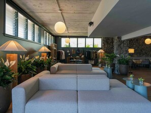 A modern interior with a seating area, large windows, and indoor plants.