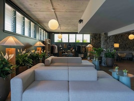 Um interior moderno com área de estar, grandes janelas e plantas dentro de casa.