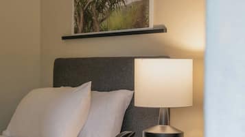 A hotel room with a bed, a bedside table with a lamp, a telephone, and a framed picture on the wall.