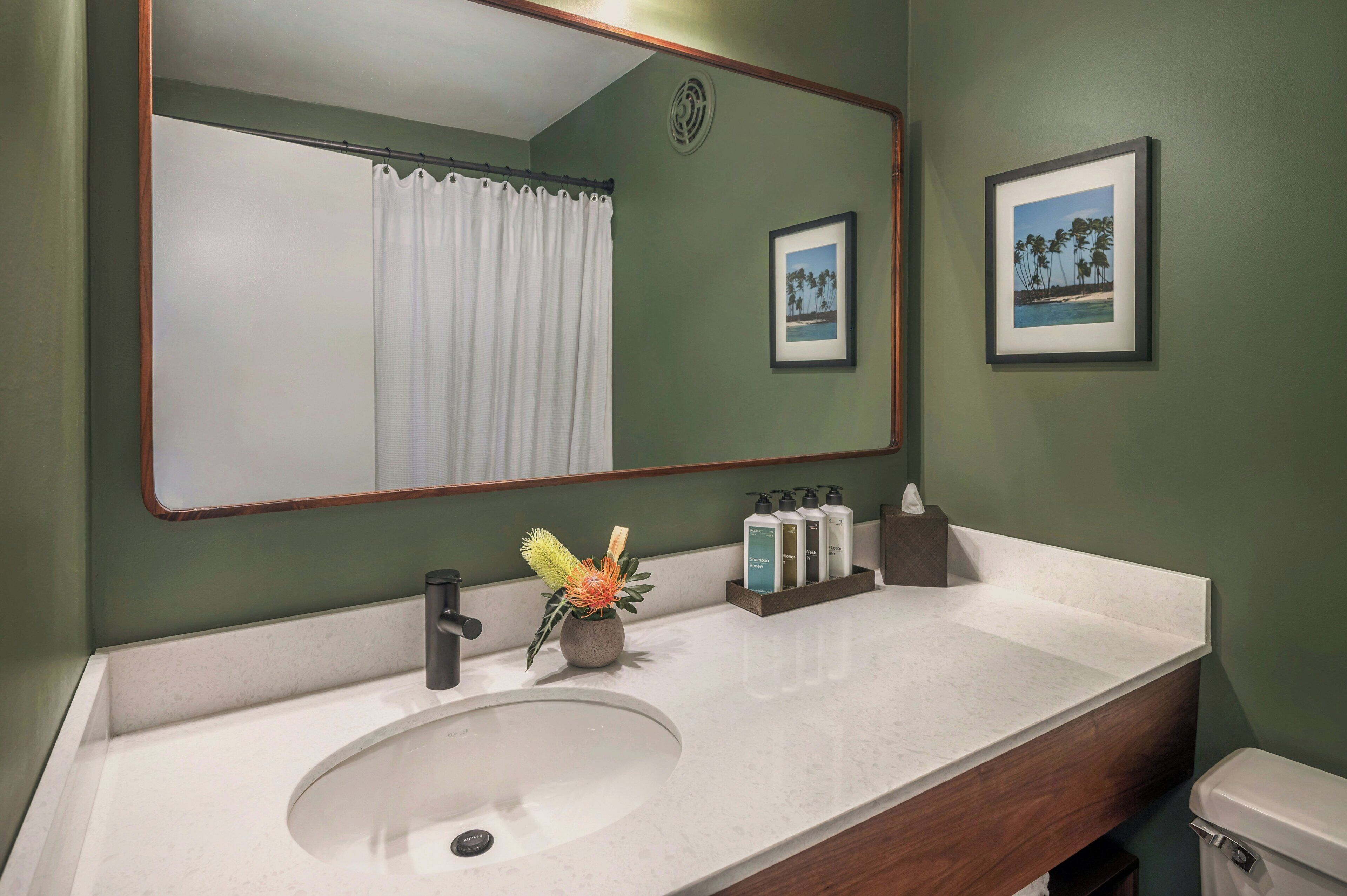 Une salle de bain avec un lavabo blanc, un miroir, des toilettes et un rideau de douche.