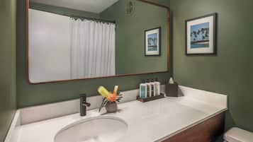 Une salle de bain avec un lavabo blanc, un miroir, des toilettes et un rideau de douche.