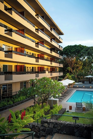 A multi-story hotel with a swimming pool, outdoor seating, and lush landscaping. - PACIFIC 19 Kona (Kailua-Kona)