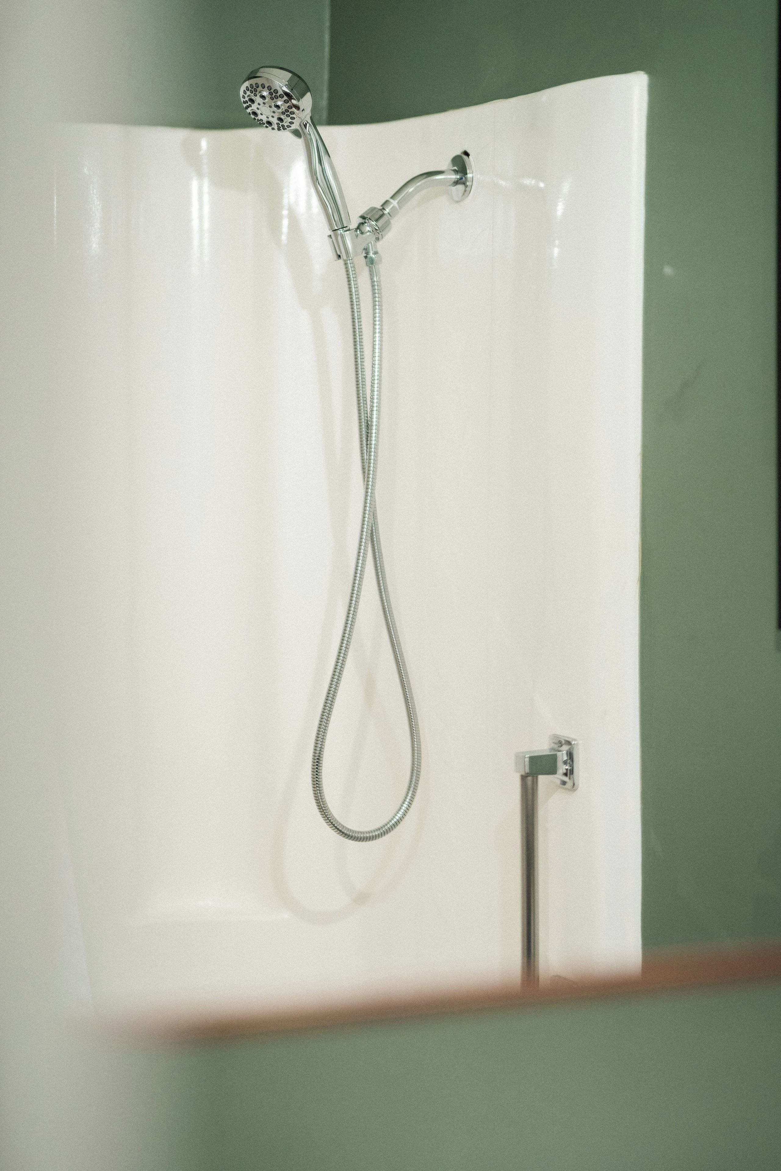 A shower with a handheld showerhead and a fixed faucet.