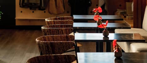 Interior de restaurante con sillas y mesas de madera, y una pared decorada con objetos colgantes.