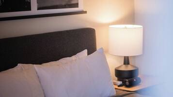 A hotel room with a bed, a nightstand with a lamp, and a framed picture on the wall.