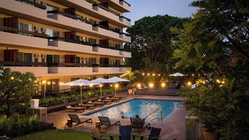 Un hotel su più piani con piscina, area salotto all'aperto e luci decorative.