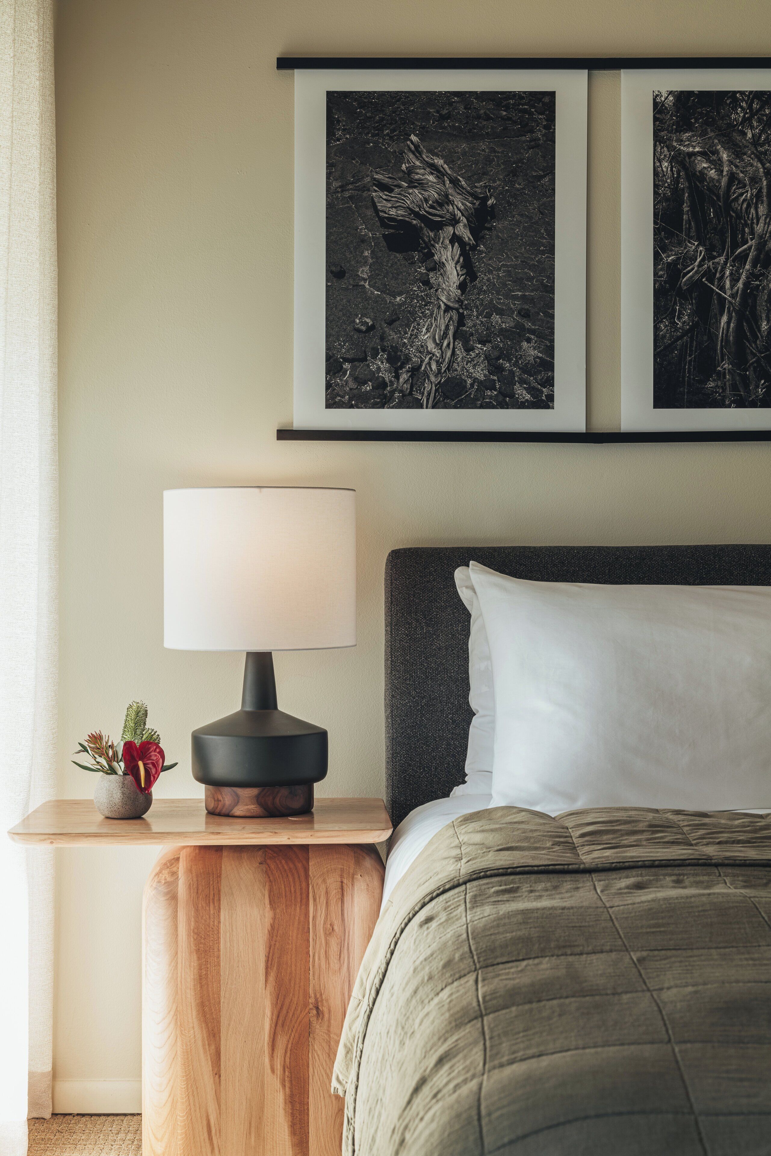 A bedroom with a bed, a nightstand, a lamp, and two framed pictures on the wall.
