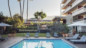 Una piscina al aire libre, sombrillas, sillones reclinables de piscina