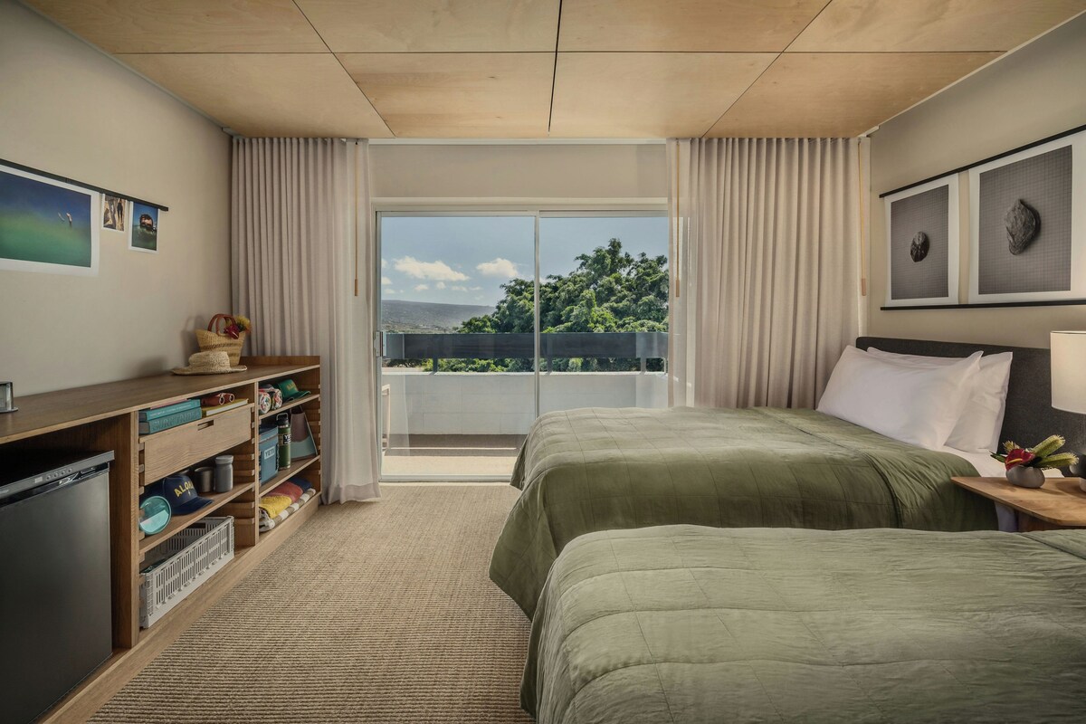 Een hotelkamer met een bed, een bureau, een boekenkast en uitzicht op het omliggende landschap.