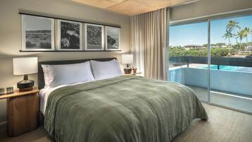 A hotel room with a bed, a nightstand, a lamp, and a large window with a view of a pool and palm trees.