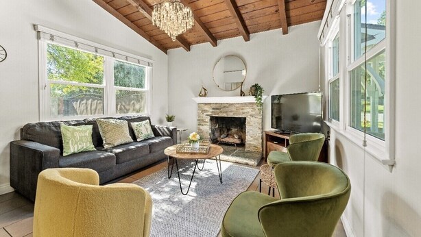 Una sala de estar con chimenea, sofá, televisor y ventanas amplias.