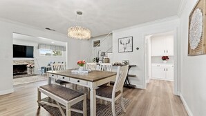 Un comedor con una mesa y sillas de madera, una araña y una chimenea.
