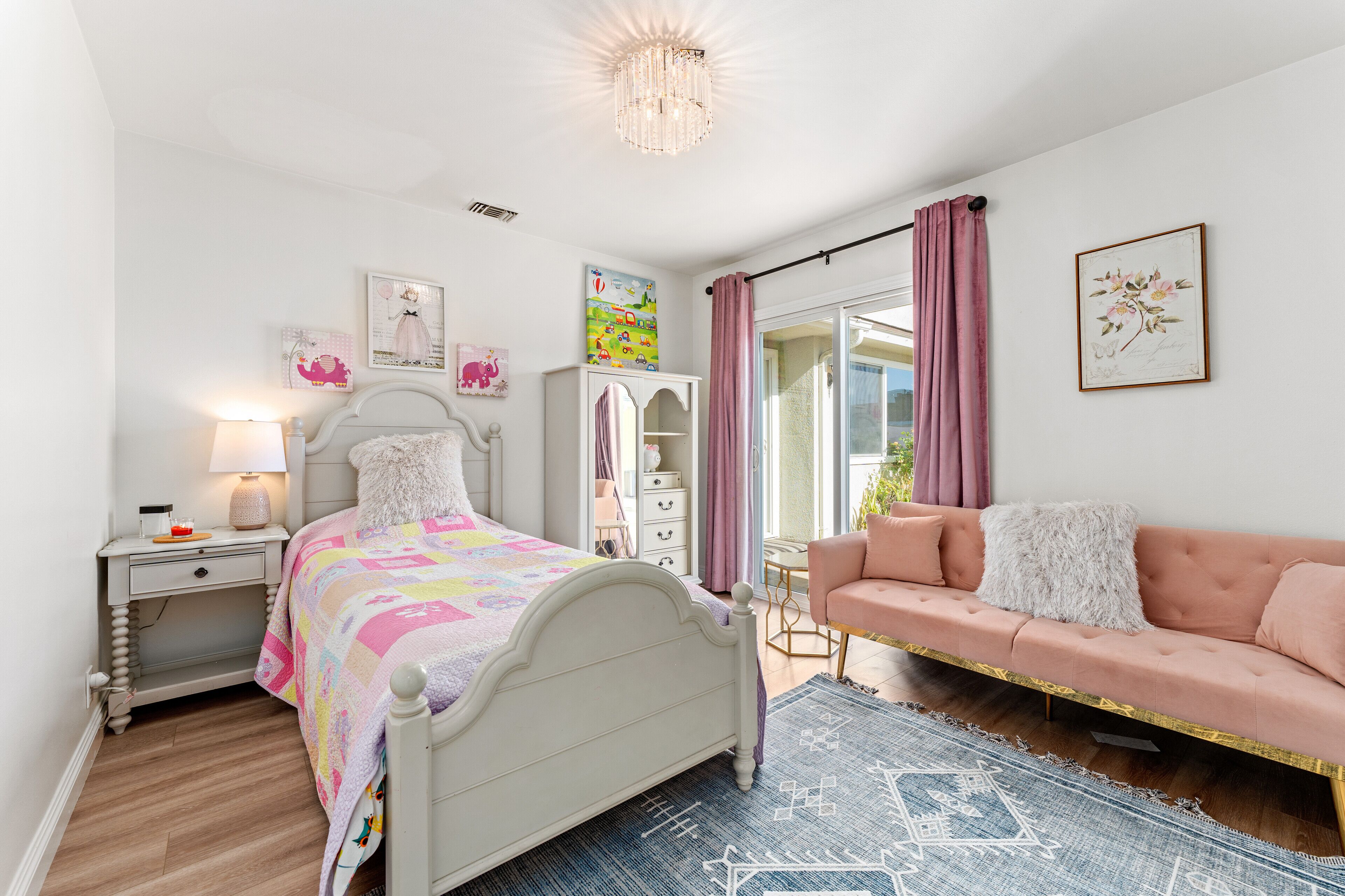 A bedroom with a bed, nightstand, dresser, and a pink sofa.