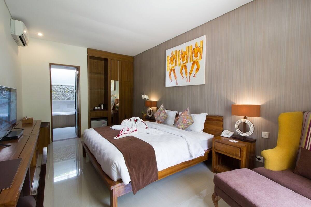 A modern hotel room with a large bed, a TV, a desk, and a chair.