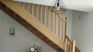 A dining area with a wooden staircase, a round table with chairs, and a bicycle decoration on the wall. - Maison 3 Chambres Proche des Plages sur la Presquile de Rhuys (Saint-Gildas-de-Rhuys)