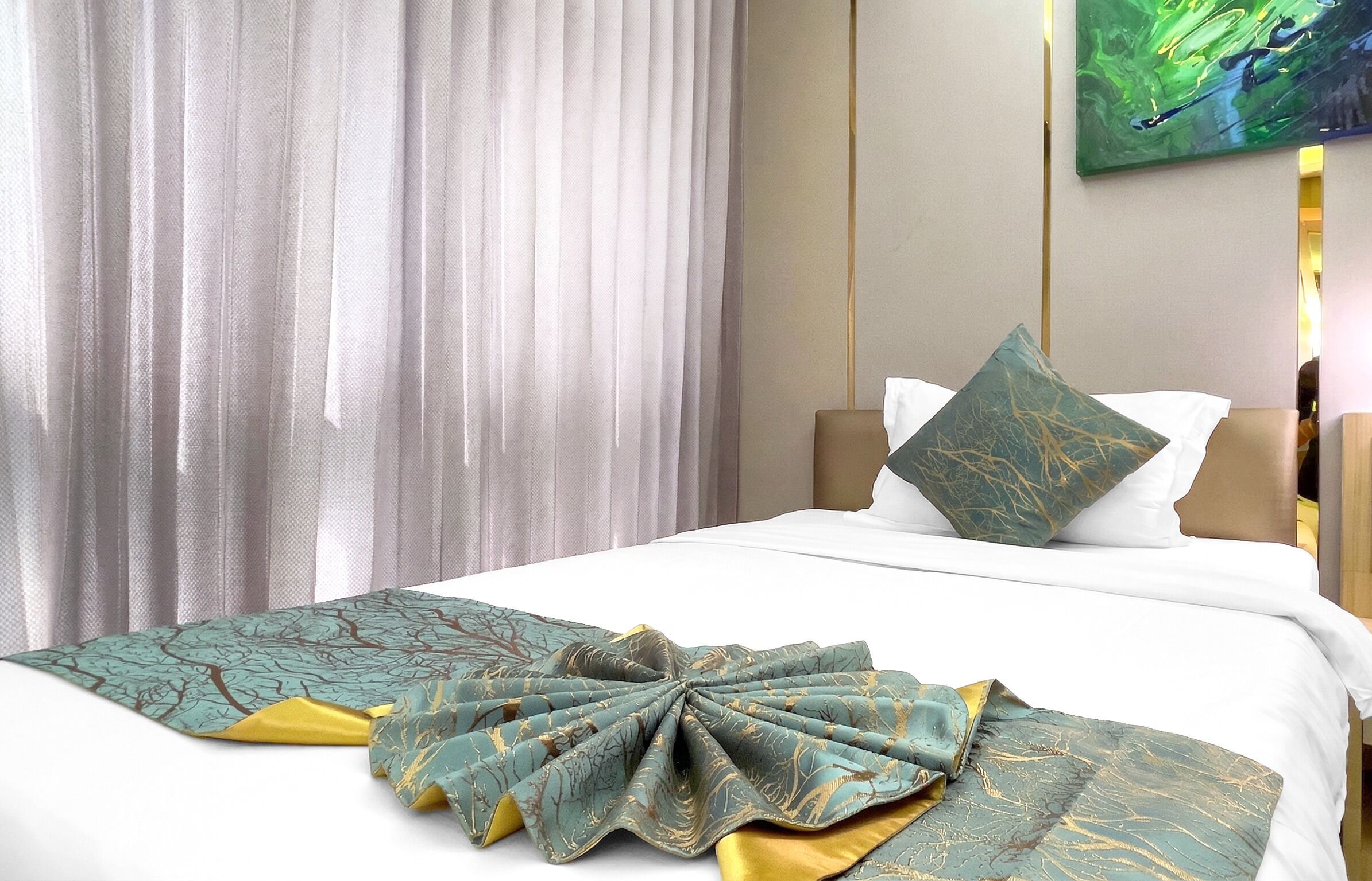 Een hotelkamer met een netjes opgemaakt bed, een groot raam met dunne gordijnen, en een schilderij aan de muur.