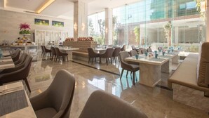 Un amplio vestíbulo de hotel con muebles modernos, ventanas grandes y un área de estar central.