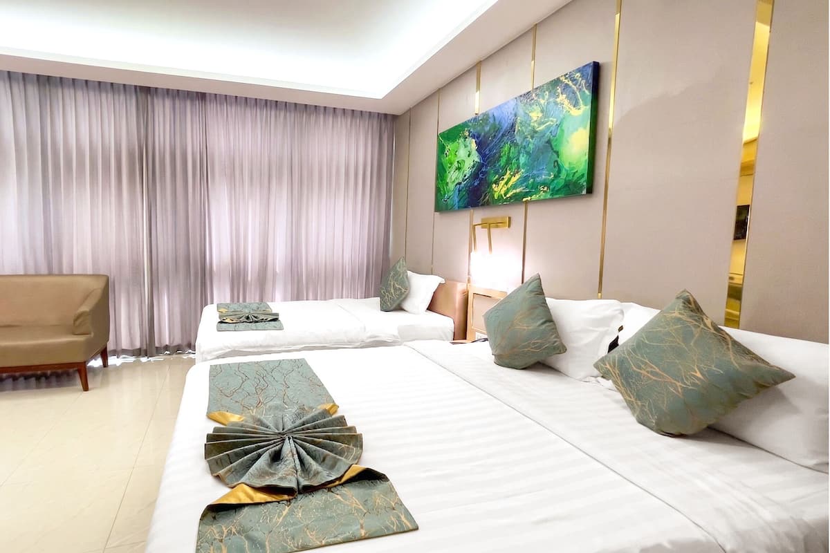 A hotel room with two beds, a sofa, a painting on the wall, and a large window with curtains.