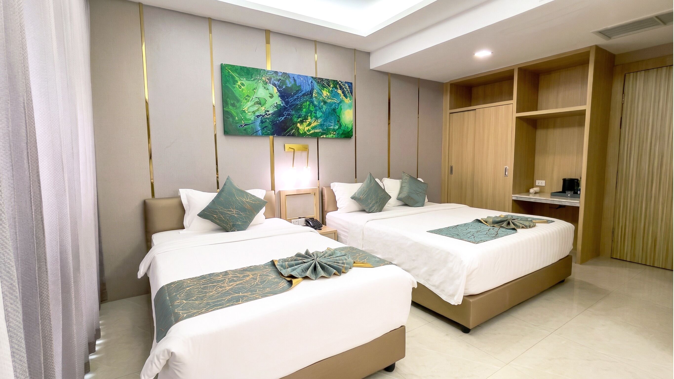 A hotel room with two beds, a desk, a wardrobe, and a painting on the wall.