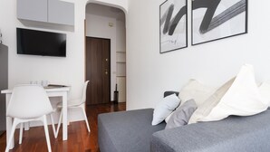A modern living room with a grey sofa, white chairs, a flat-screen TV, and abstract artwork on the wall. - Italianway Easy - Carlone 5 (Milan)