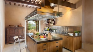 A modern kitchen with a central island, stainless steel appliances, and wooden cabinetry. - Pieve di San Giovanni 10 (Pomarance)