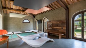 A modern spa room with a pool, wooden walls, and large windows. - Pieve di San Giovanni 10 (Pomarance)