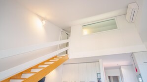 Een modern interieur met een houten trap, witte muren en ingebouwde kasten.