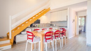 Een moderne keuken met witte kasten, een houten trap en een eethoek met rode stoelen.