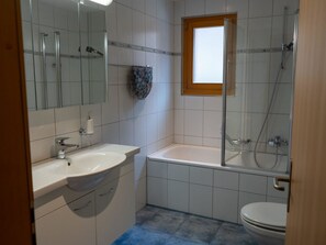 Un baño con lavamanos, espejo, ducha e inodoro.