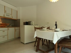Uma cozinha compacta com armários brancos, micro-ondas e cafeteira no balcão.