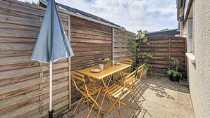 A wooden fence, a table with chairs, and a blue umbrella in a backyard. - Les Bégonias by Interhome (Saint Malo)