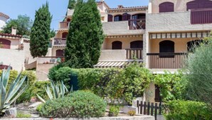 A multi-story building with balconies, a garden with various plants, and a stone facade. - Les Cyprès by Interhome (Bandol)