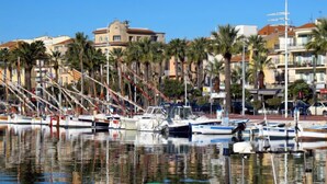 A marina with boats docked, palm trees, and buildings in the background. - Les Cyprès by Interhome (Bandol)