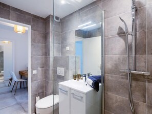 Une salle de bain moderne avec une douche à parois de verre, un lavabo blanc et des toilettes.