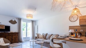 Uma sala de estar moderna com um sofá, cadeiras, uma mesinha e uma televisão.