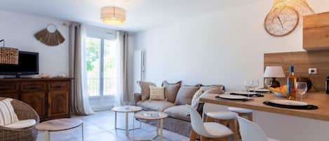 Ein modernes Wohnzimmer mit einer Couch, Sesseln, einem kleinen Tisch und einem Fernseher.