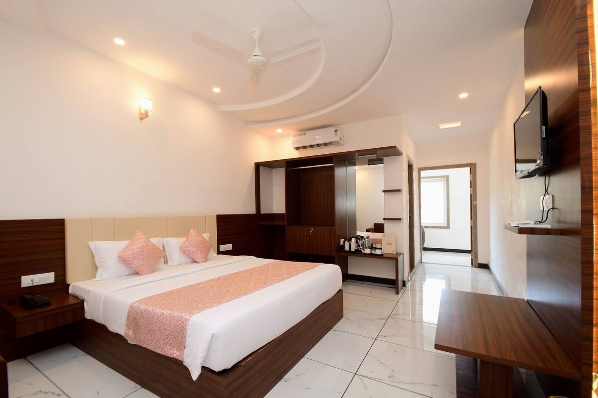 Quarto de hotel moderno com uma cama grande, uma escrivaninha, um guarda-roupa e uma TV na parede.