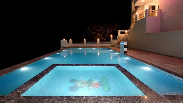 Una piscina con un mosaico de un personaje de caricatura, una escalera y un edificio con balcón.