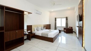 Una habitación de hotel con una cama grande, un armario, un escritorio, una silla y un televisor.