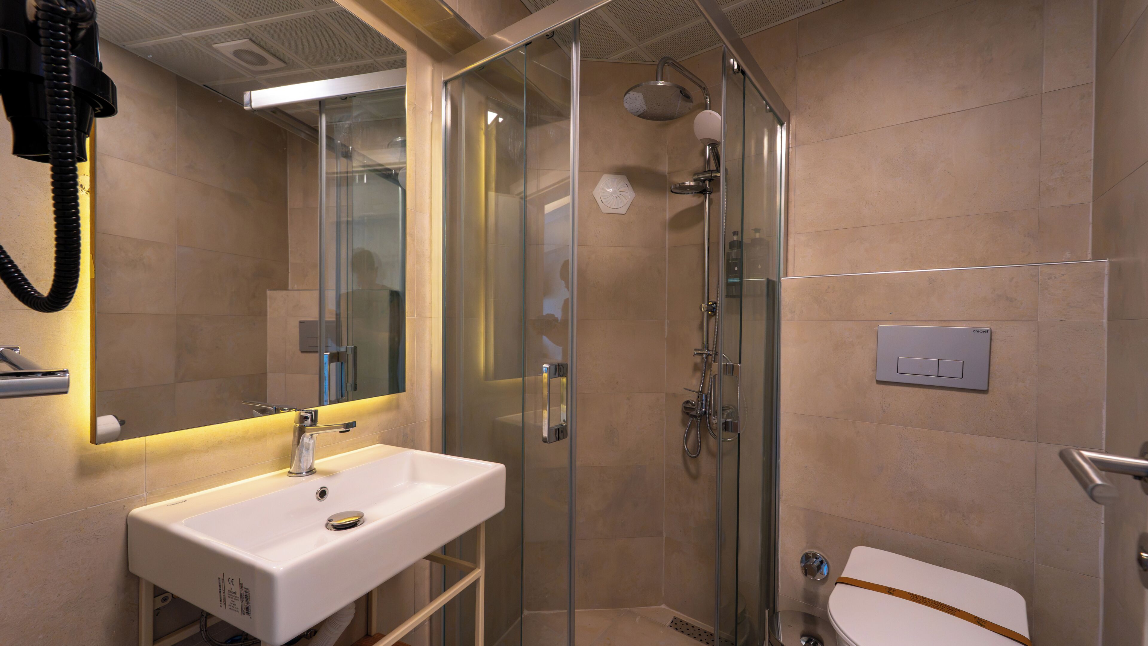 Un baño moderno con ducha de vidrio, lavamanos blanco y un inodoro.