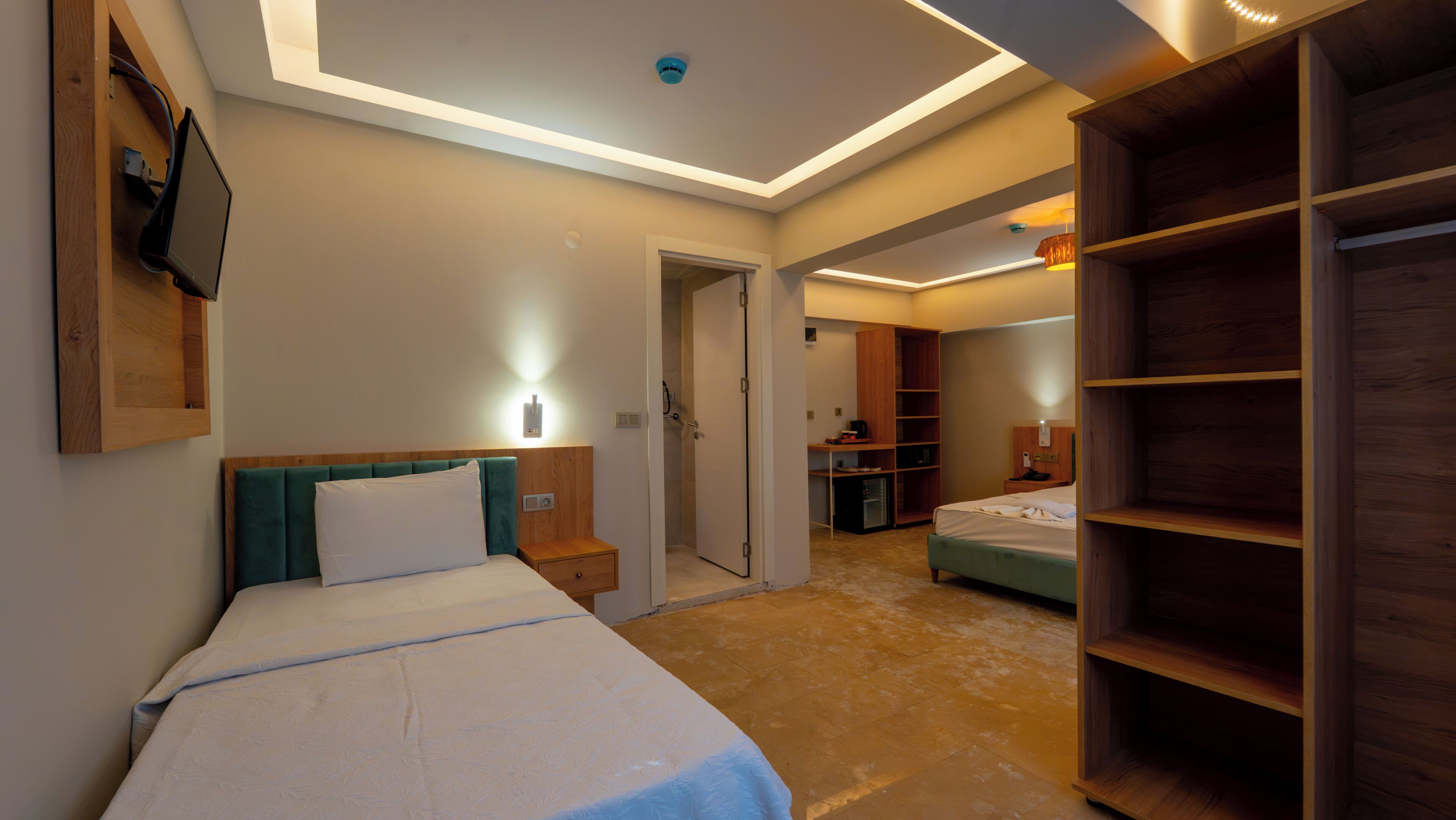 Habitación de hotel con cama, mesitas de noche, escritorio, armario y zona de ducha.