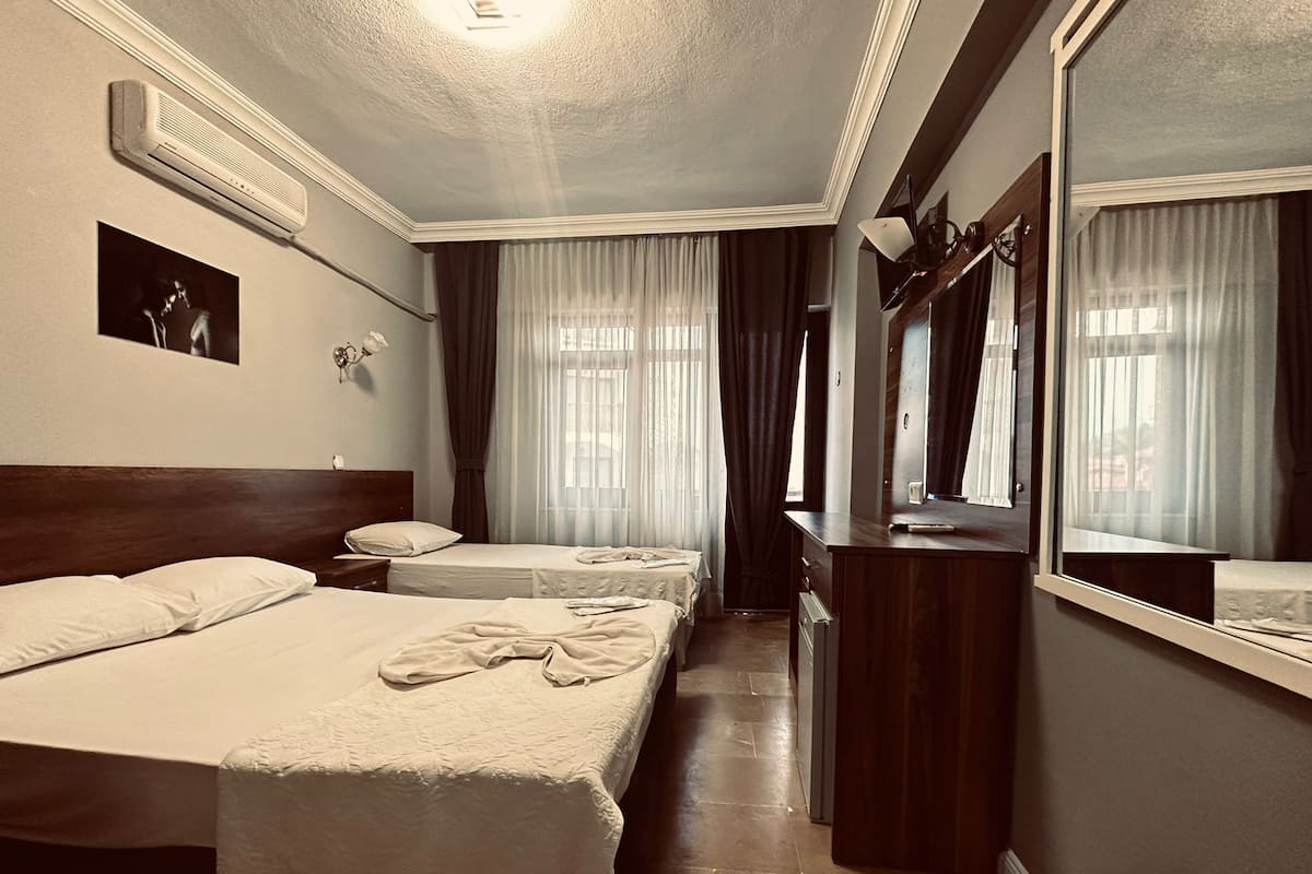 Habitación de hotel con dos camas, un aparador, un espejo y un ventilador de techo.