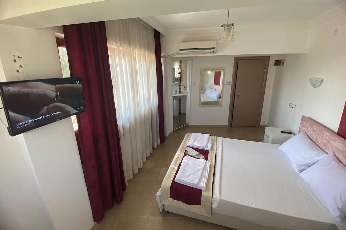Habitación de hotel con cama, televisión montada en la pared, baño con espejo y aire acondicionado.